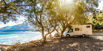 an RV parked on the shore of a lake