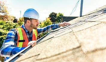 a man wearing a hard hat and safety vest pointing at a wall