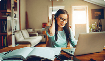 a person sitting at a desk with a laptop and books