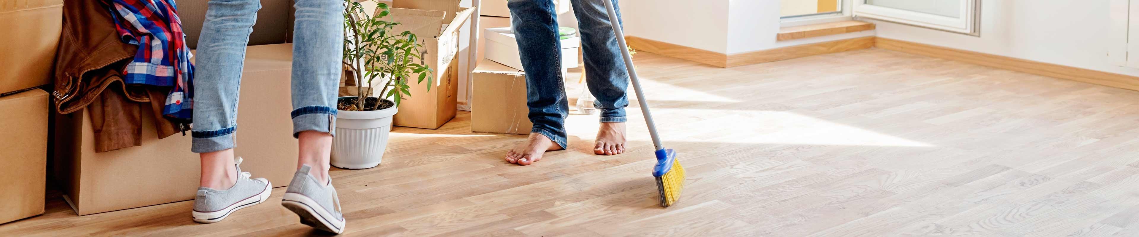 a couple on hardwood floors with moving boxes nearby