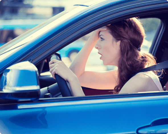 A shocked person behind the wheel of her vehicle.