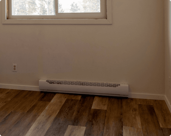 A close-up of an installed electric heater in a bedroom.