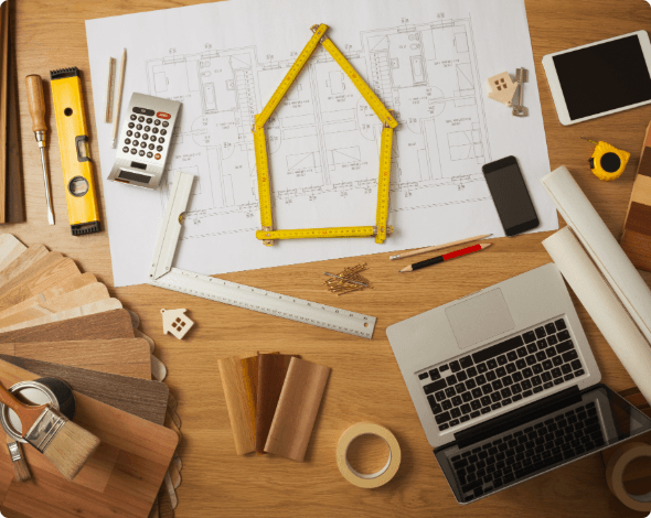 A desk covered in home blueprints, building materials and a laptop.