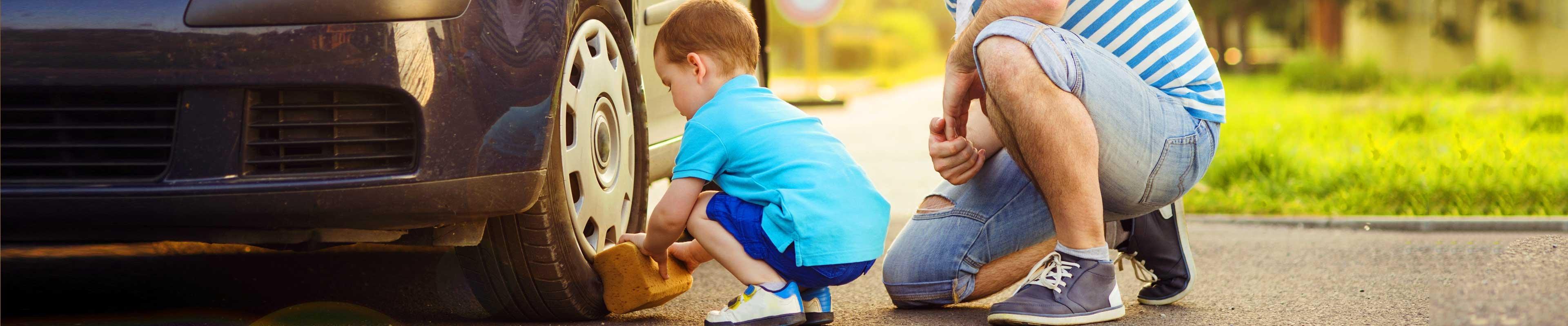 Little boy washing a car with his dad.