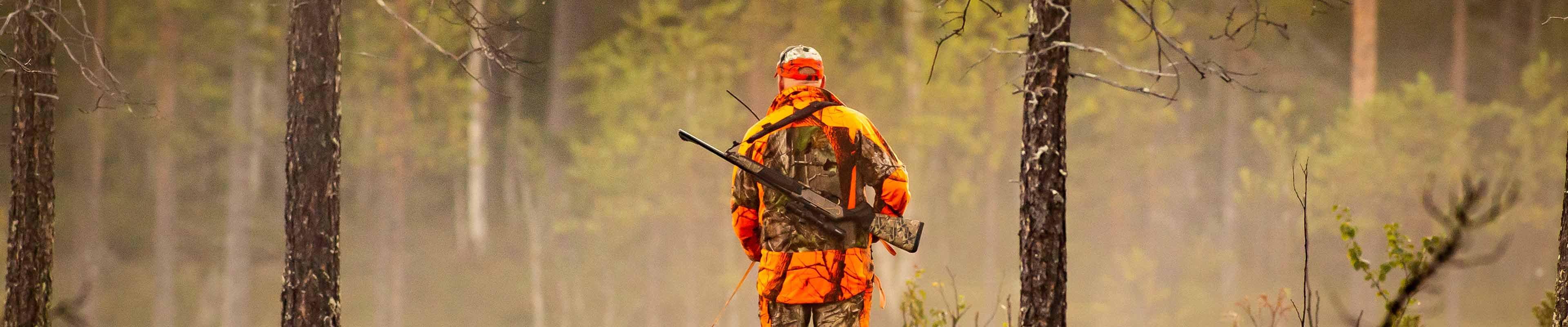 Hunter carrying rifle practicing hunting safety.