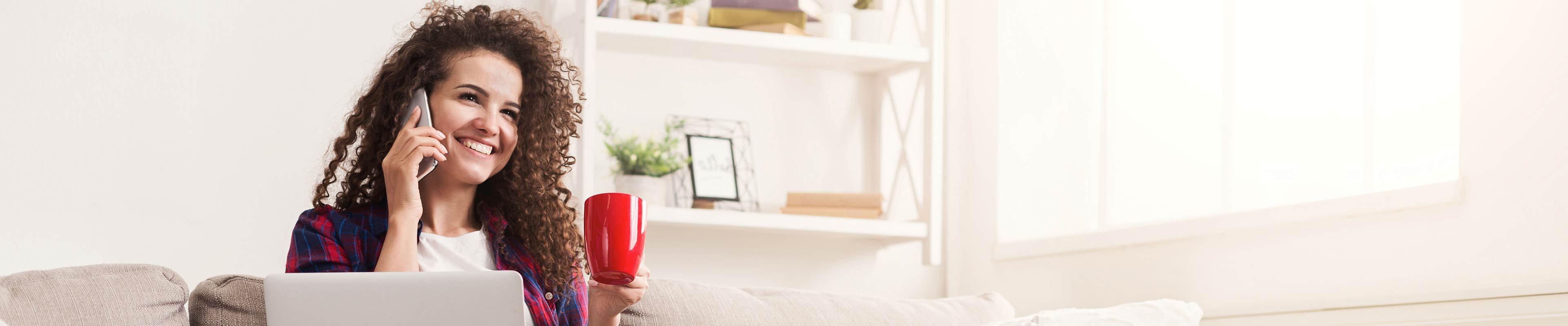 A woman drinking coffee, chatting on the phone with a friend.