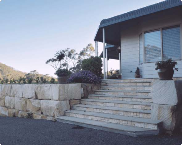 Image of a home entry with stairway and retaining wall, hill off in the distance