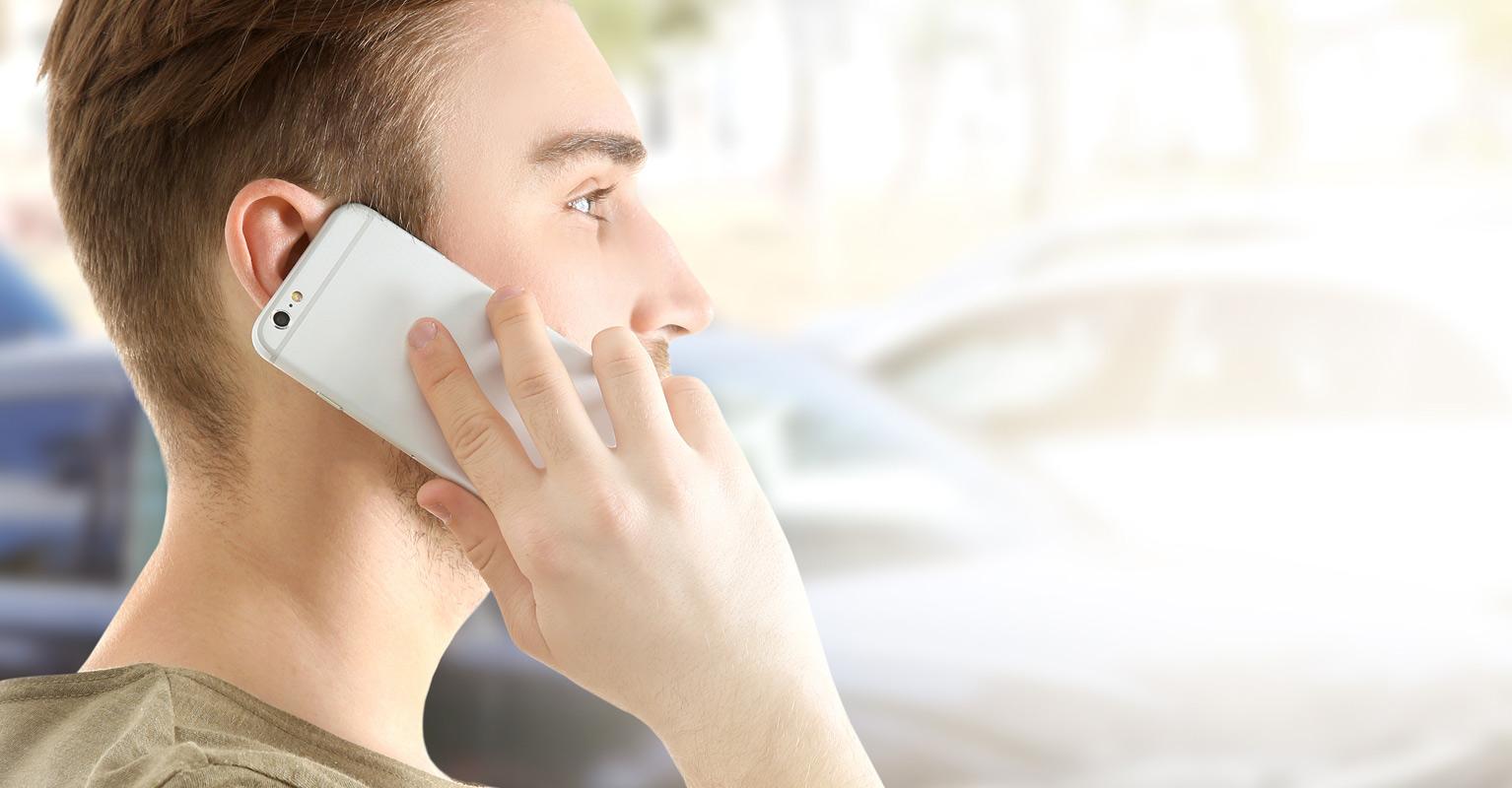 Young man talking on phone after an accident with uninsured driver