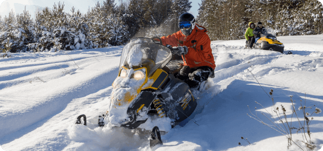 Two snowmobiles riding around each other