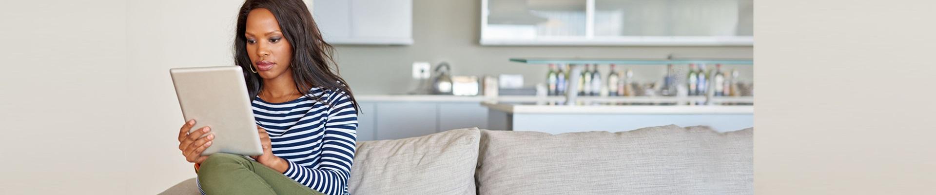 a woman sitting on a couch holding a tablet